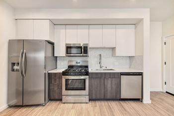 Kitchen with Refrigerator, Hardwood Inspired Floors, Oven, Cabinets and Microwave